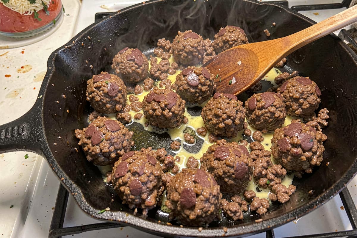 Golden-brown hidden beef liver bites in a black cast iron skillet with melted butter and flaked salt