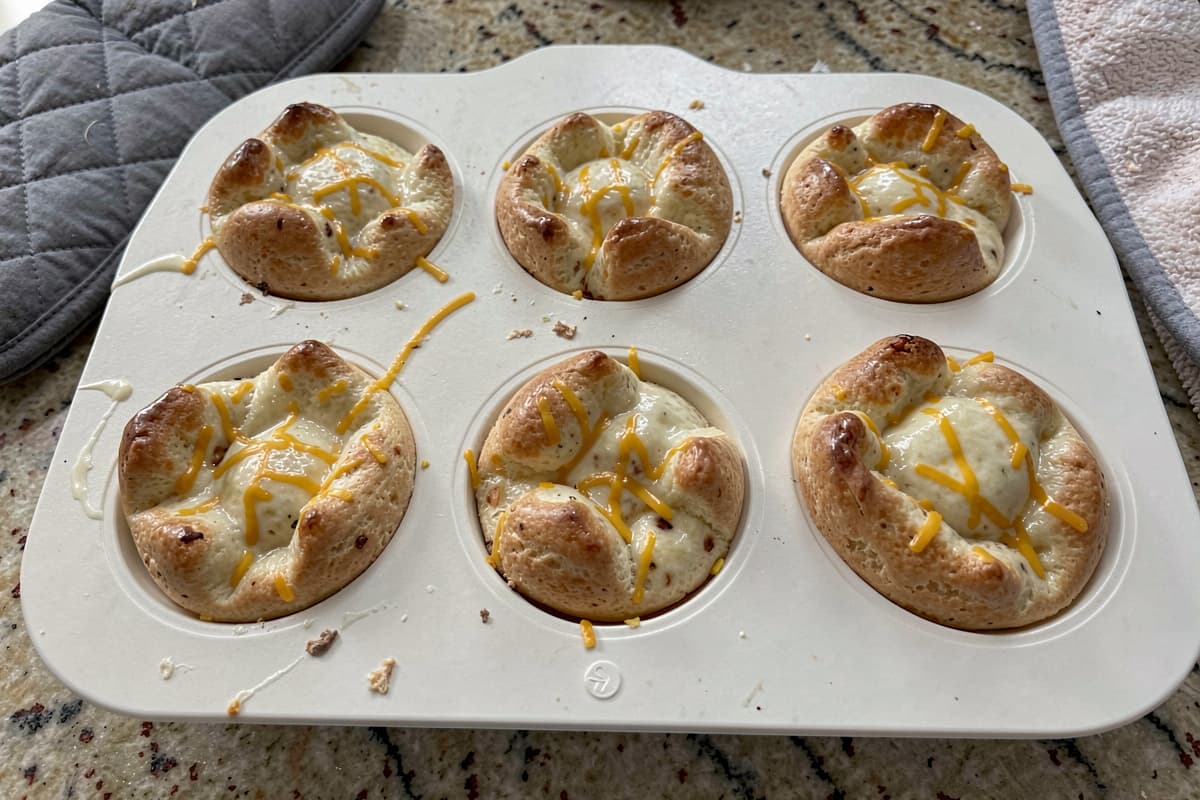 Six silky carnivore egg bites in a white silicone mold, glossy custardy tops with visible cheese flecks