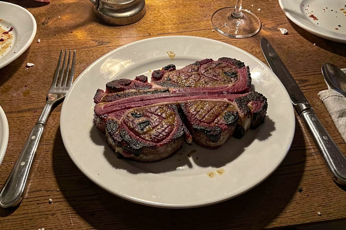 Pan-seared chuck eye steak with deep brown crust and pink medium-rare interior on dark slate, butter melting on top