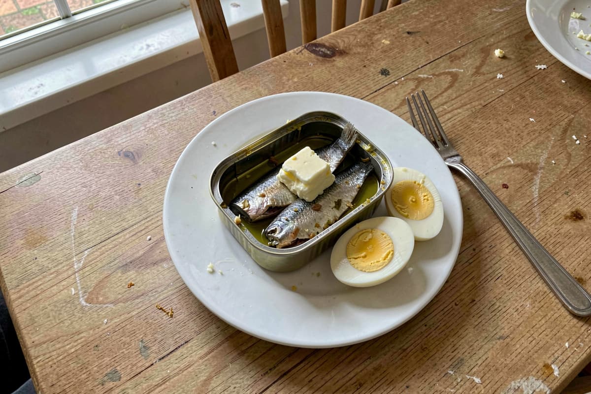 Five-minute carnivore sardine plate with an open tin of sardines in olive oil, halved hard-boiled eggs, and a pat of butter