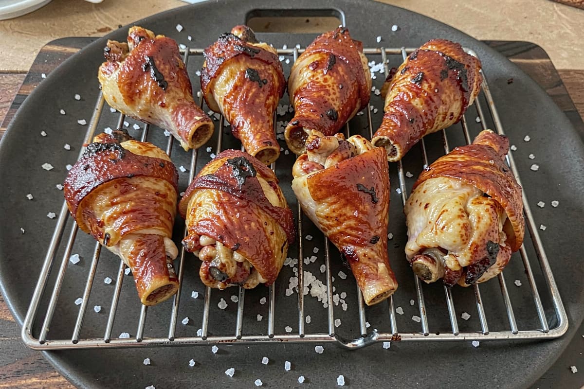 Tray of bone-in smoked chicken thighs with deep amber crispy skin, juicy meat visible at the bone end, salt scattered on the wooden board