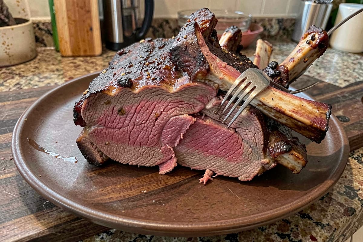 Bone-in beef short ribs after 72-hour sous vide and final sear, deep brown crust on the outside, rosy medium-rare interior, fork pulling apart the tender meat